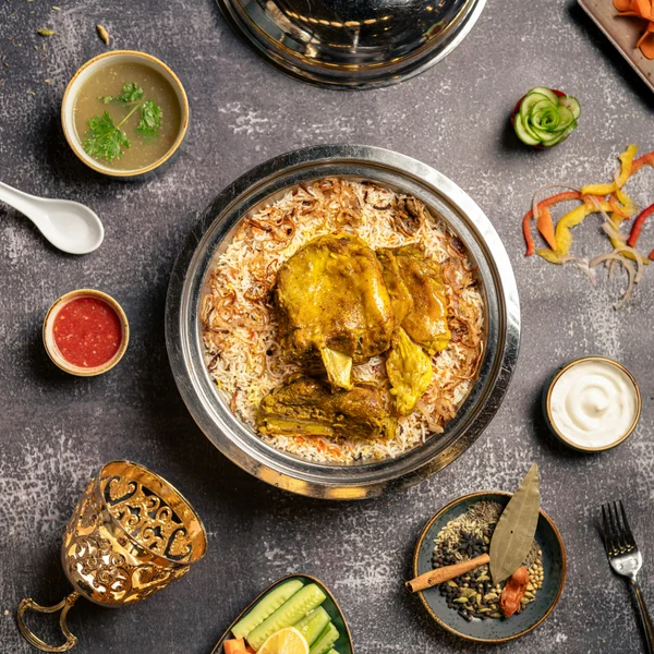 Rich goat biryani with tender bone-in pieces over basmati rice on a banana leaf