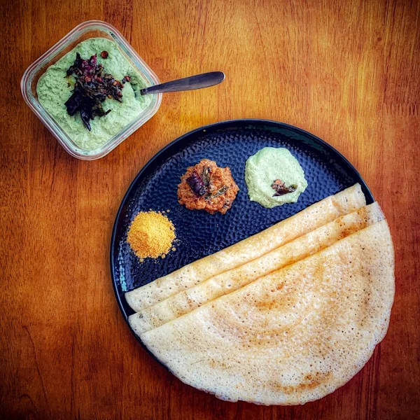 Crispy golden masala dosa with coconut chutney and sambar on a segmented stainless steel plate